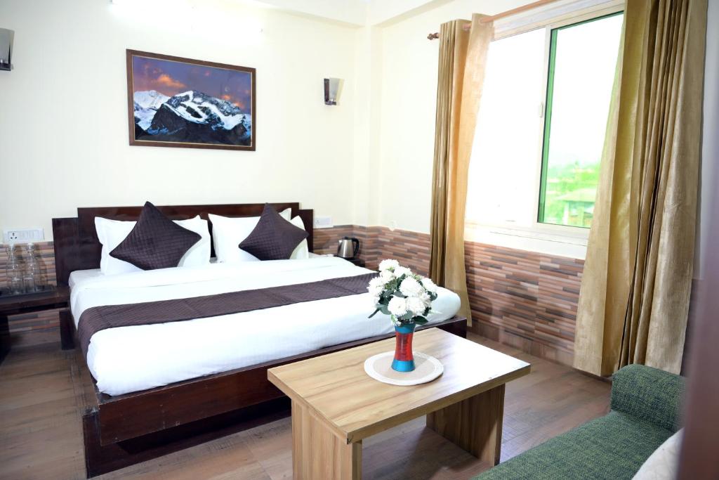 a hotel room with a bed and a vase of flowers on a table at Panch Aarohan Hotel King in Pithorāgarh