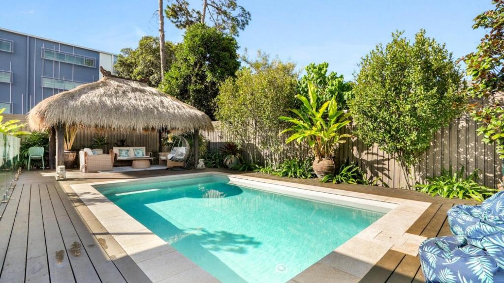a swimming pool in a backyard with a thatch roof at The Cabana Oasis in Woorim