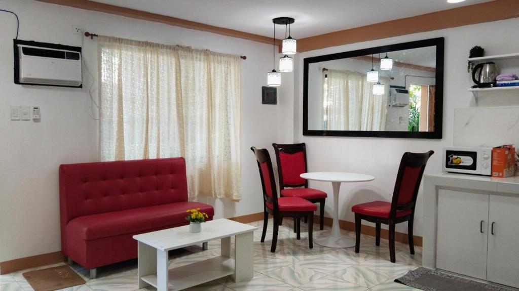 a living room with a red couch and chairs and a table at RM Apartments in Idanao