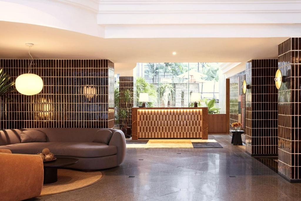 A bright lobby lounge with a sofa, round table, and reception desk.