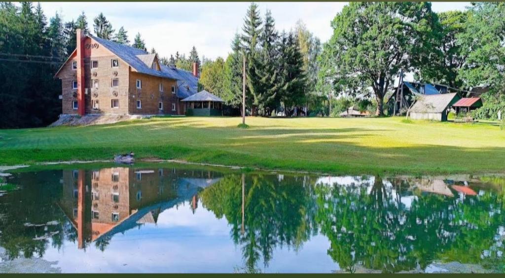 a house on a golf course with a reflection in the water at Kryzbarkas in Degučiai