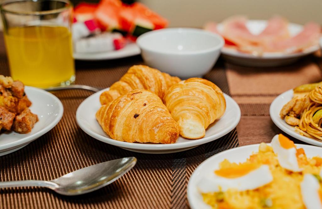 A close-up breakfast spread centered on croissants and assorted hot and cold dishes.
