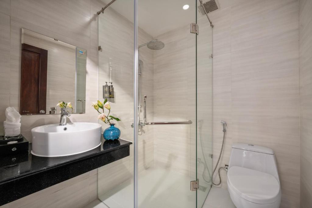 A compact tiled bathroom with a vessel sink, enclosed glass shower, and toilet.