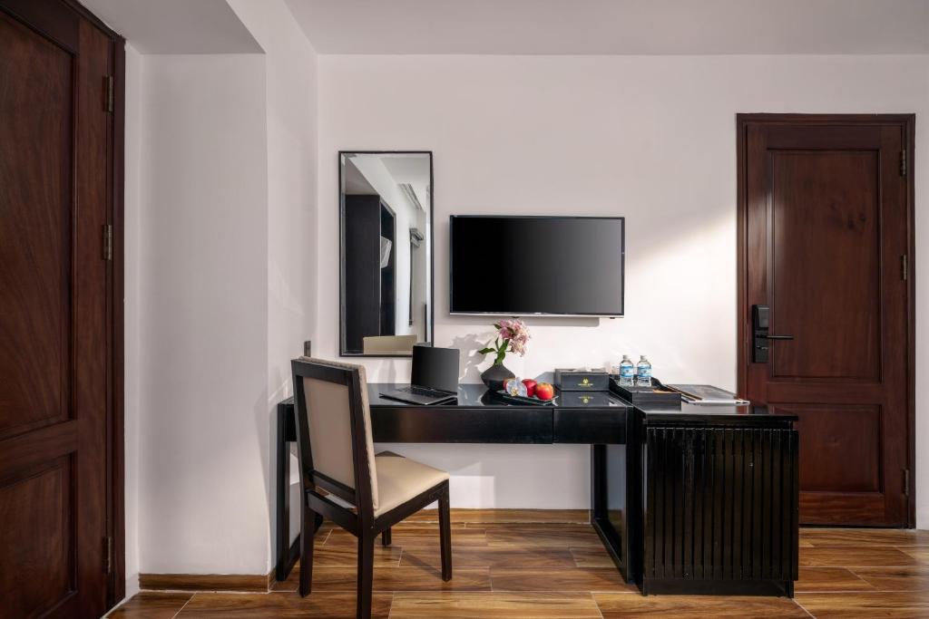 A compact in-room desk and chair beside a television and minibar area.