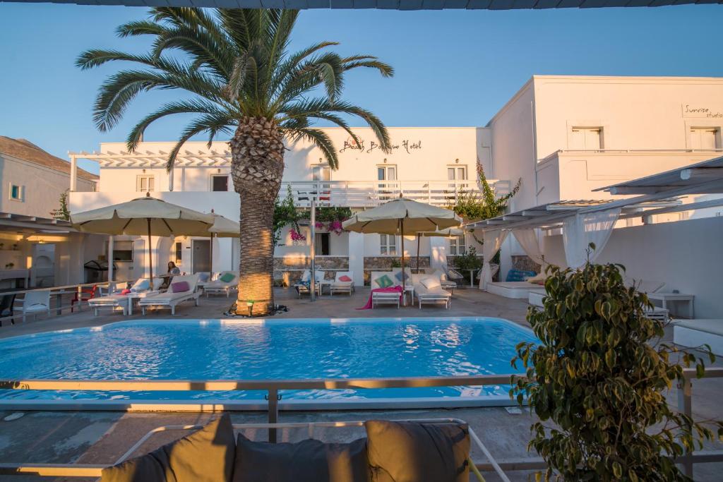 uma piscina com uma palmeira, cadeiras e guarda-sóis em Beach Boutique Hotel em Kamari