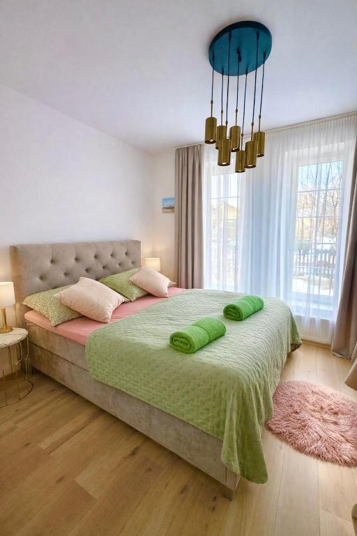a bedroom with a large bed with green sheets at Libás Apartman in Keszthely