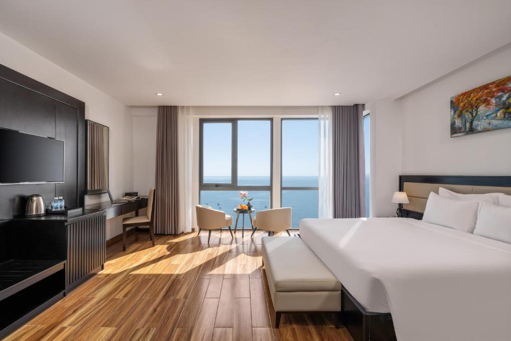 A sea-view bedroom with a large bed, television wall and compact work area.