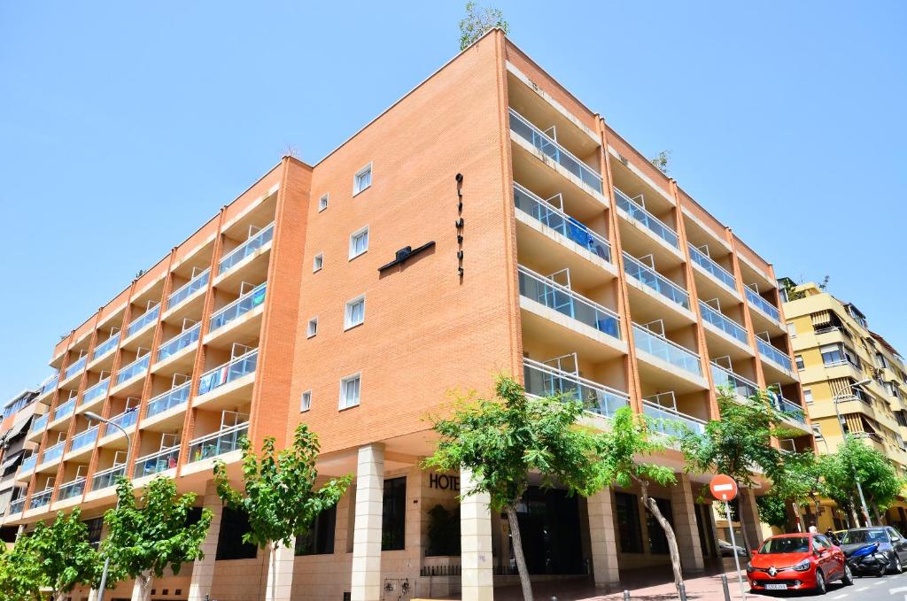 een groot bakstenen gebouw met bomen ervoor bij Hotel Olympus in Benidorm