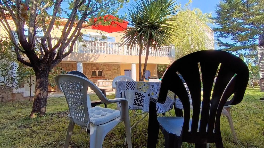 three chairs sitting next to a table in a yard at Maison au calme avec jardin et piscine Saint Raphaël in Saint-Raphaël