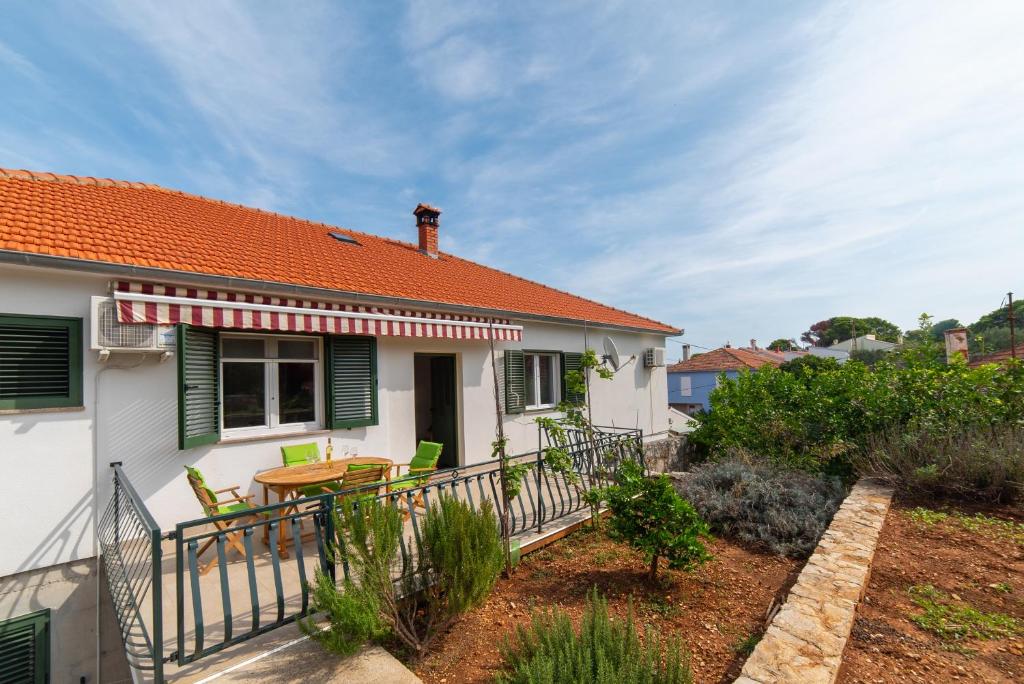 a house with a balcony with a table and chairs at Nikola's spacious apartment in Božava