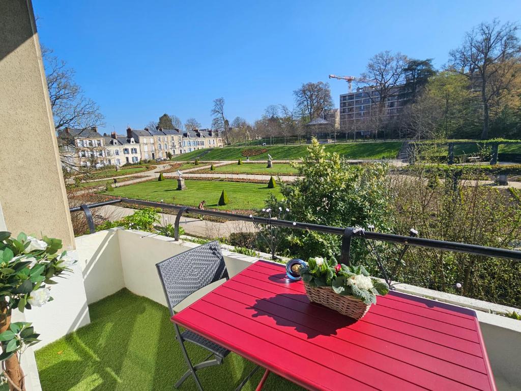 a red table on a balcony with a view of a park at La Roseraie in Le Mans
