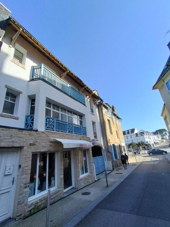 a white building with a balcony on a street at Ptit salé Quiberon in Quiberon