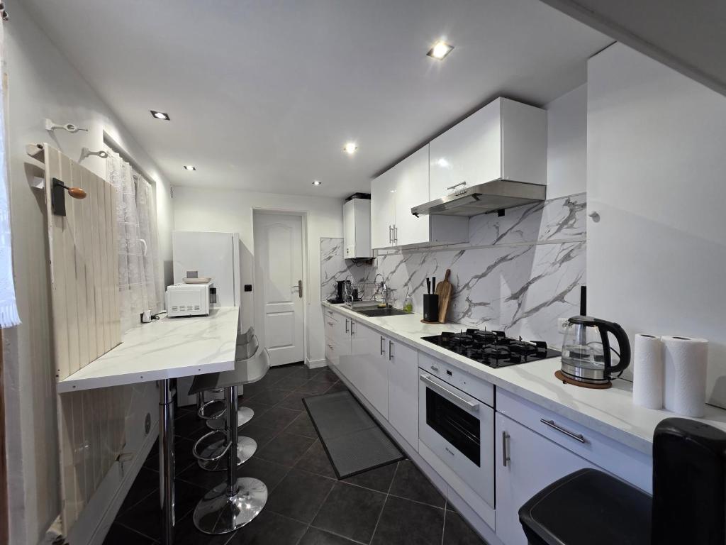 a kitchen with white cabinets and a stove top oven at Maison de ville entièrement équipée in Argenteuil