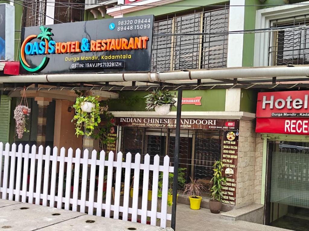 a hotel with a white fence in front of a building at Oasis Hotel and Restaurant in Siliguri