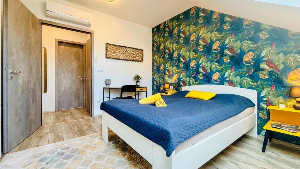 a bedroom with a blue bed with a painting on the wall at Aurora Apartman in Kőszeg