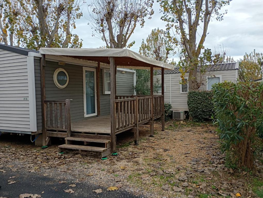 a house with a porch with an umbrella at Mobile-Home L'Instant Marin in Sérignan