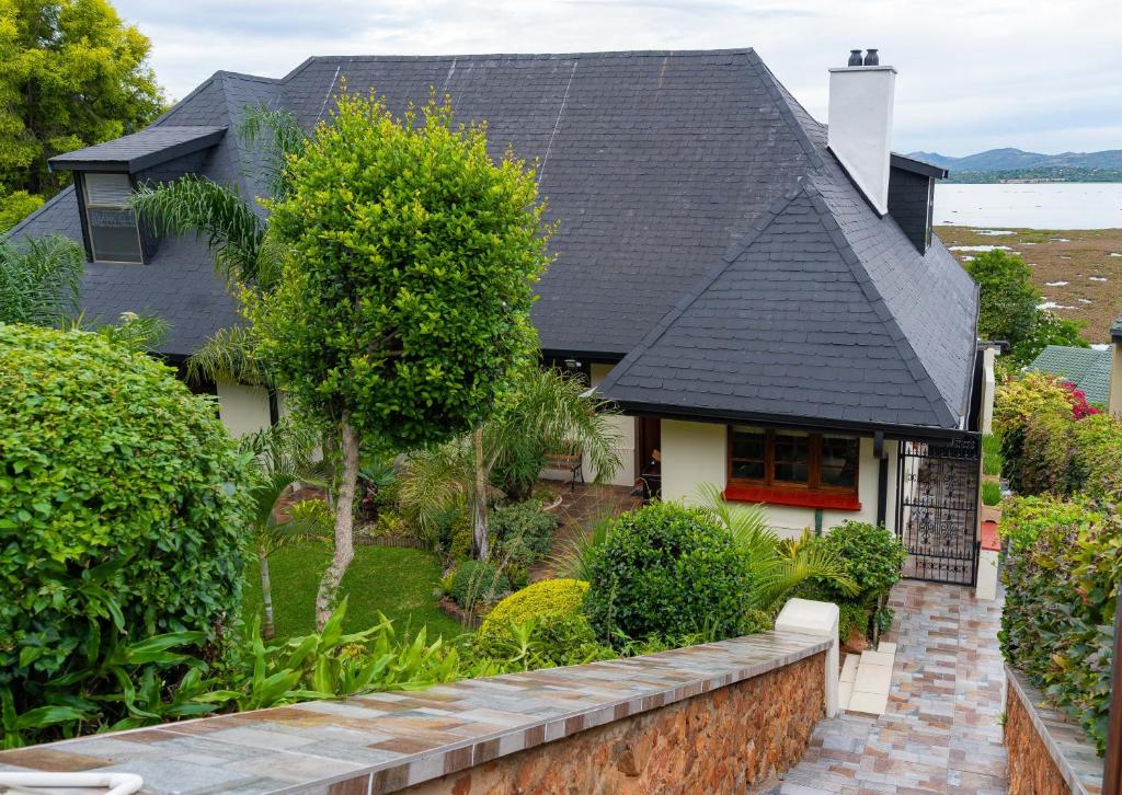 a house with a black roof and a brick wall at Hoyozela in Hartbeespoort