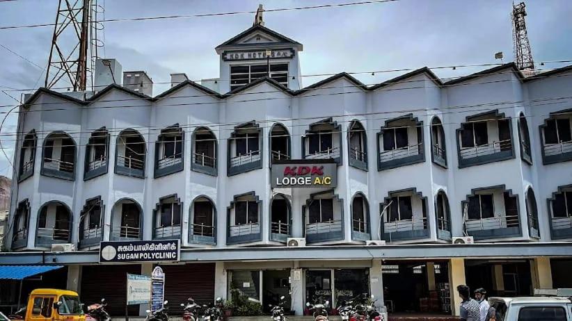 a large white building with a sign on it at Kdk lodge in Pollāchi