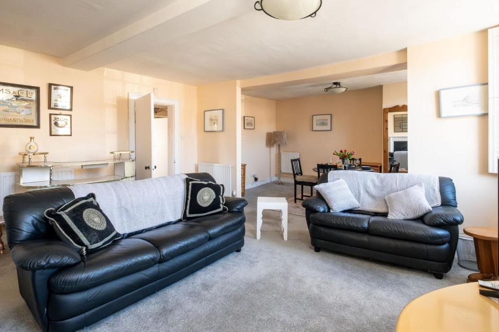 a living room with a leather couch and a table at Hill House Apartment in Framlingham