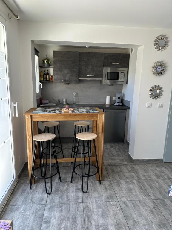 a kitchen with a counter and bar stools at LAVANDE studio 4 personnes in Château-Arnoux-Saint-Auban