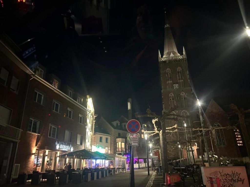 a city street at night with a clock tower at Hotel am Markt Eschweiler in Eschweiler