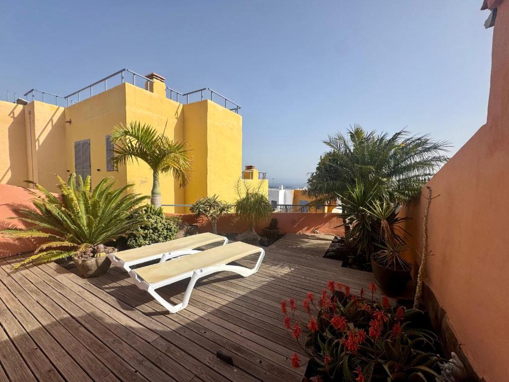 a white bench on a wooden deck with plants at Montaña Blanca - Casa Bimba in Caleta De Fuste