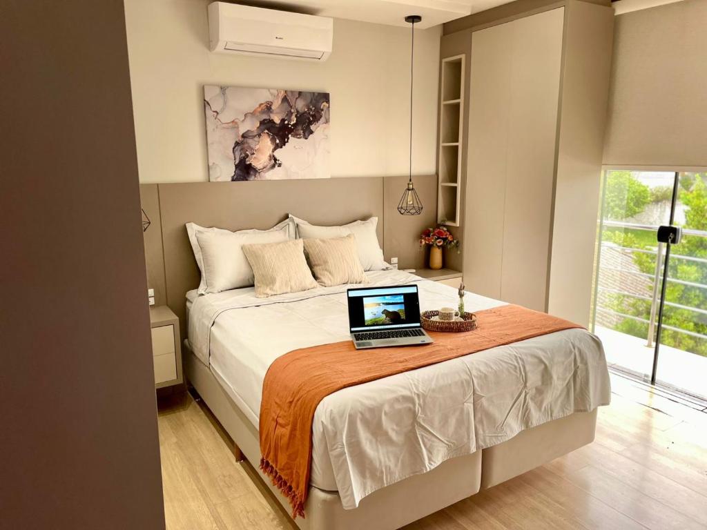 a bedroom with a bed with a laptop on it at Villa Serena Garden - Suíte com Hidromassagem - Ideal Casal in Cascavel