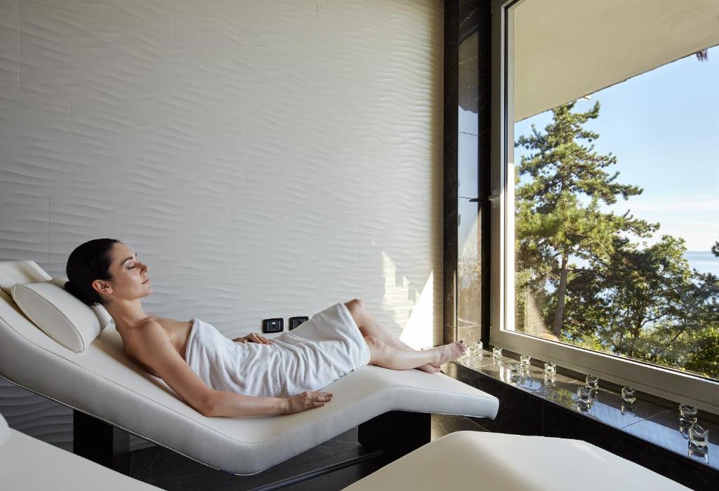 a woman sitting in a chair in a room with a window at Hotel Riviera & Maximilian's in Trieste