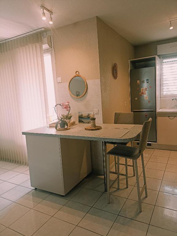 a kitchen with a counter and a table and chairs at Mauguio-Carnon Apt T2 Tout Confort, Spacieux, Lumineux, Clim, Wifi, Balcon, parking privé, 15 mn des plages, de Montpellier in Mauguio