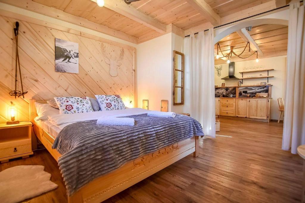 a bedroom with a bed and a wooden wall at Tatra Góral Ski Apartament in Murzasichle