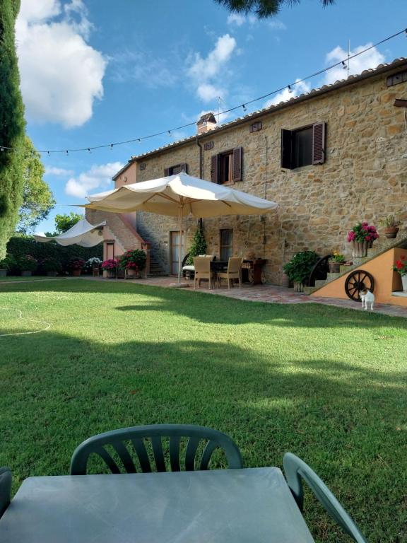 a table with chairs and an umbrella in front of a building at Casa Carini in Scansano