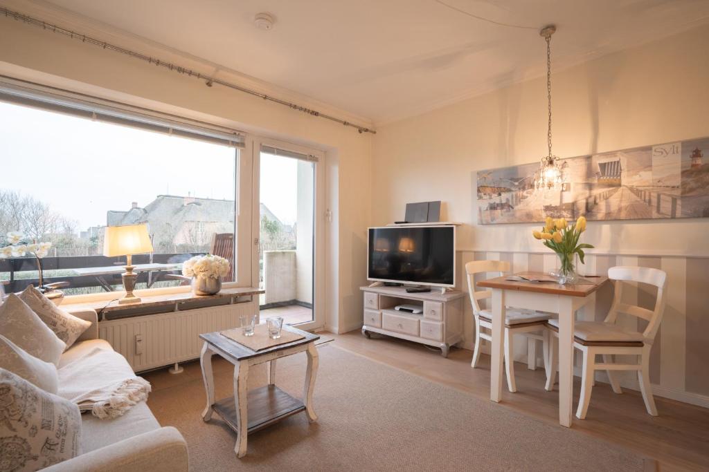 a living room with a couch and a table and a tv at Deichblick in List