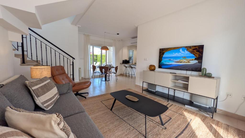a living room with a couch and a tv on a wall at Villa with private pool and BBQ on Mar Menor Golf Resort in Torre-Pacheco