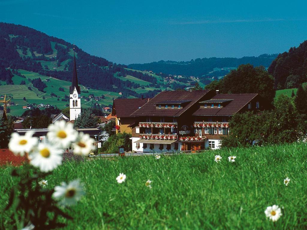 a building on a hill with a field of flowers at S'Matt 3 in Lingenau