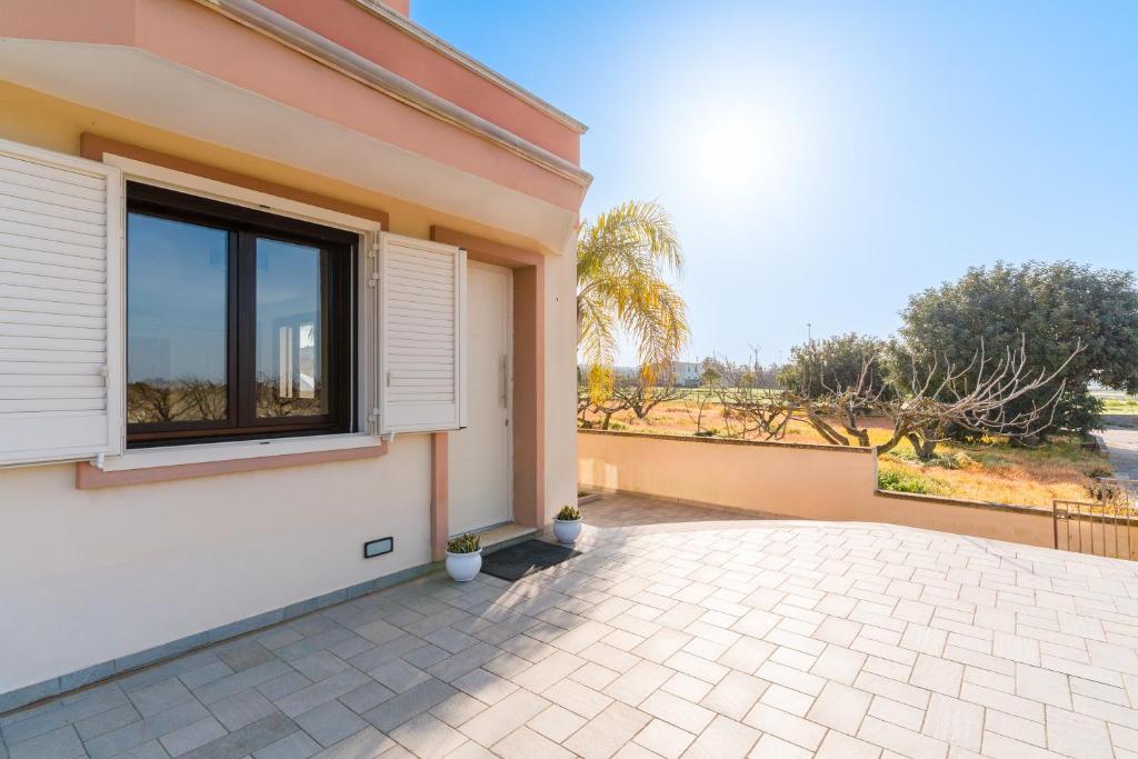 a house with a window and a patio at Intera villa ad uso esclusivo con 2 bagni 4 camere da letto,garage,giardino,area fitness,lavatrice,wifi in Tuglie