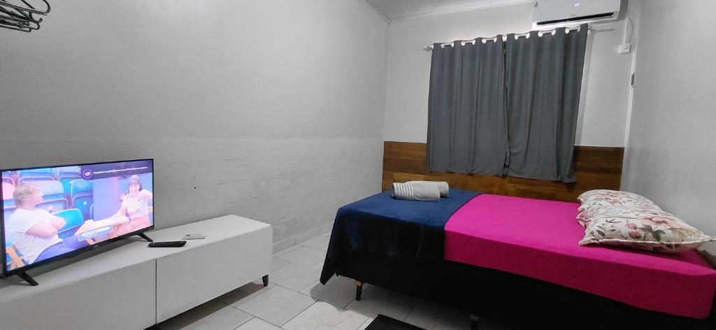 a bedroom with a bed and a flat screen tv at Pousada familiar 05 in Rio do Sul