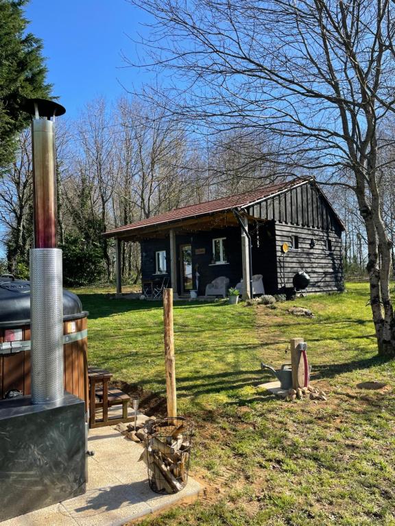 a log cabin with a wood stove in front of it at Gite La Chouette met hottub in Beyssac