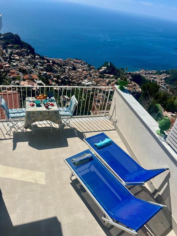 a balcony with blue chairs and a table and the ocean at Casa Damico in Castelmola