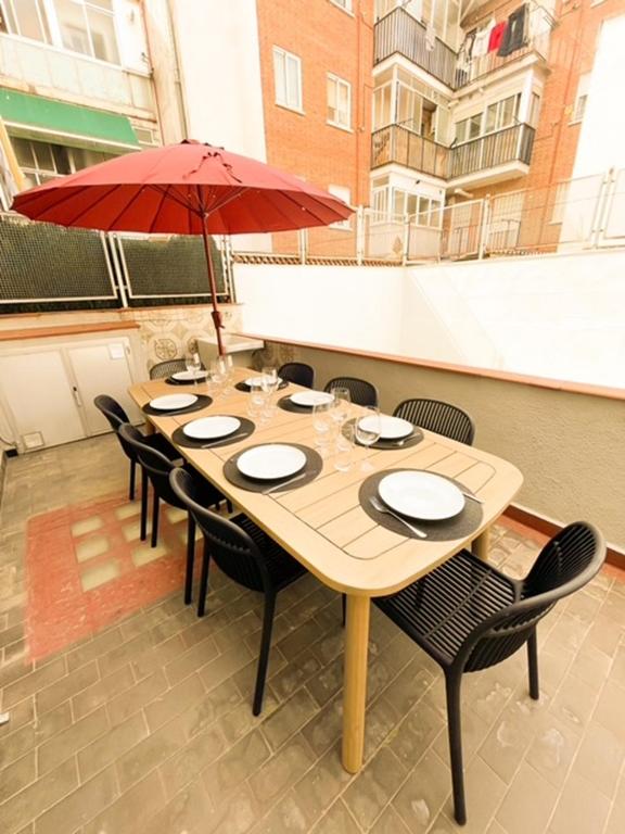 a wooden table with chairs and a red umbrella at Contemporary Chic with Terrace & Balcony in Madrid