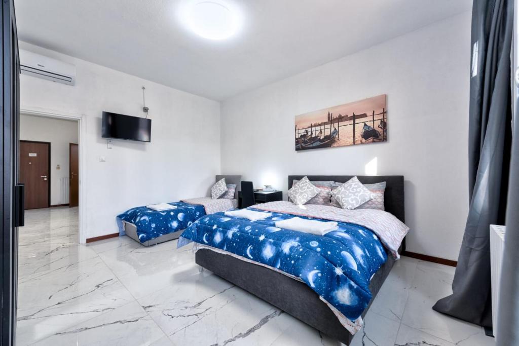 a bedroom with two beds and a television in it at Cesare Room in Apartment in Marghera