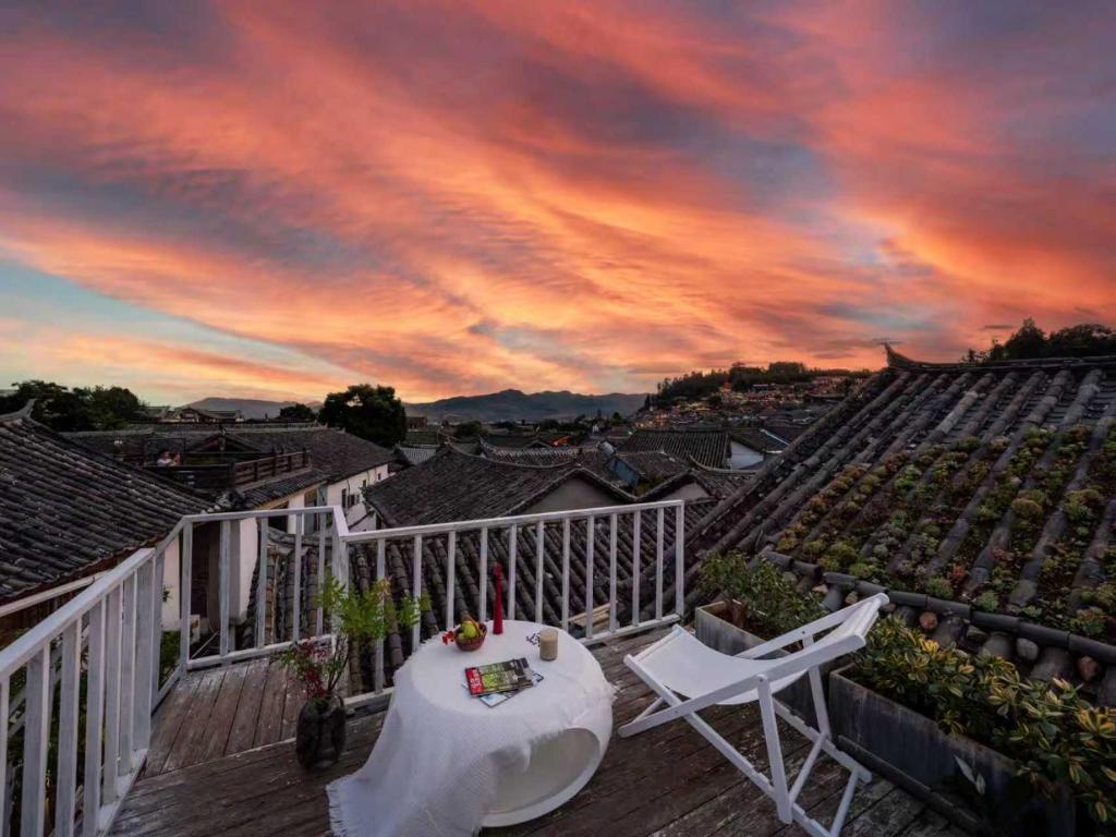 a deck with a table and chairs and a sunset at Sunlit Snow Mountain Z Naxi Ethnic Style Courtyard in Lijiang