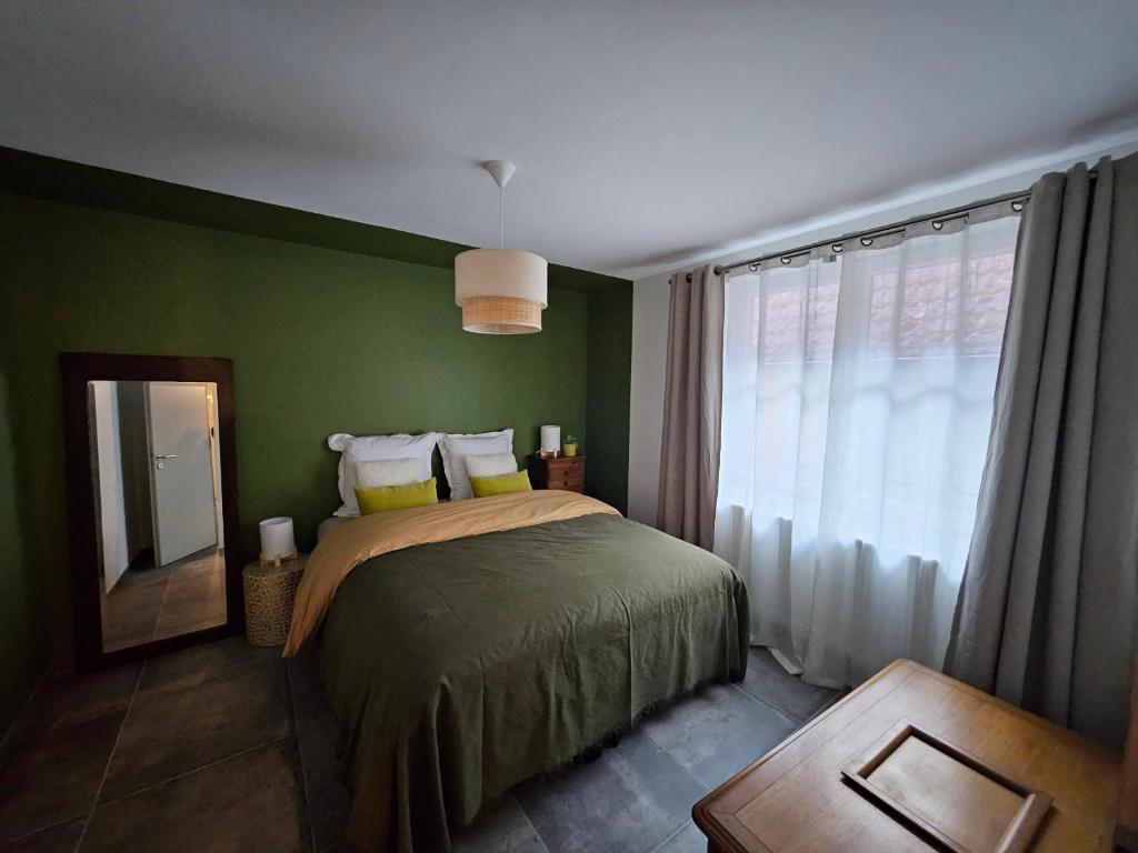 a bedroom with a bed with green walls and a window at Appartement Le petit Bretzel in Neuwiller-lès-Saverne
