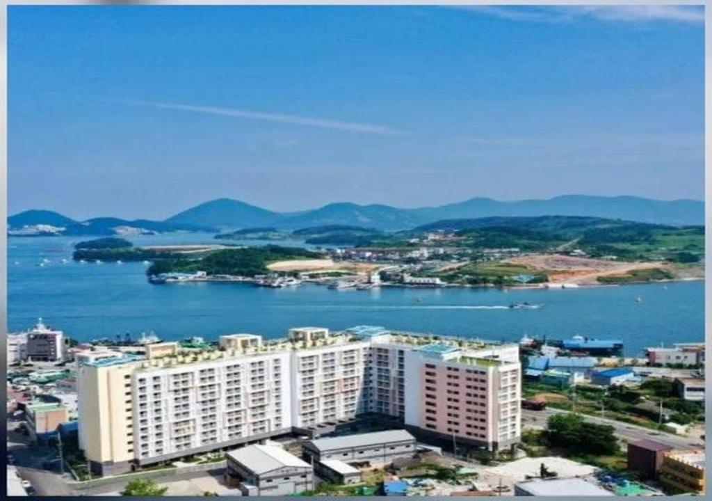 a large white building next to a large body of water at Hoya stay in Yeosu