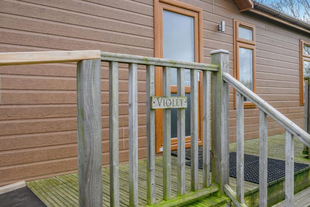 a wooden railing with a sign on a house at Primrose 2 bed - Violet in Eye