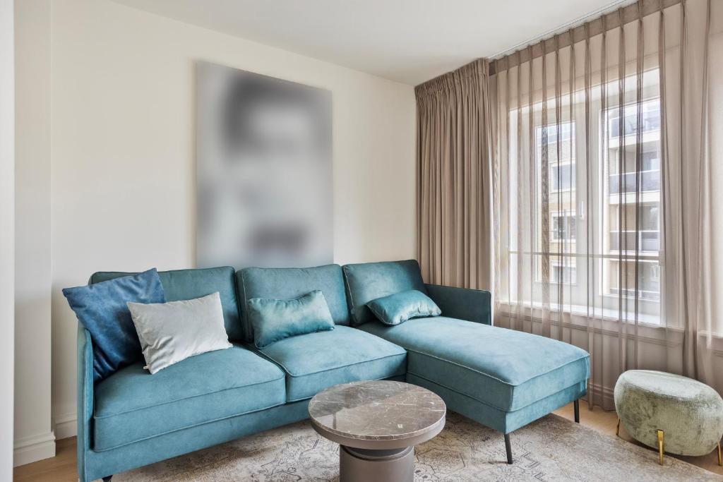 a blue couch in a living room with a window at Eindhoven City Suites Hoogstraat B 4P in Eindhoven