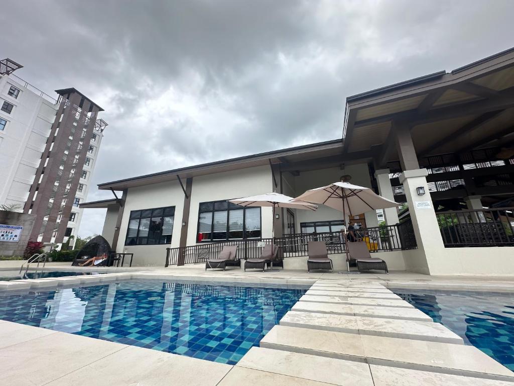 a pool with chairs and umbrellas in front of a building at Azure Edge in Dauis