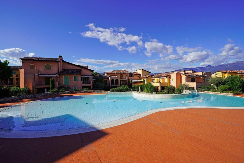 a large swimming pool in a yard with houses at Borgo Del Torchio - Gardagate in Manerba del Garda
