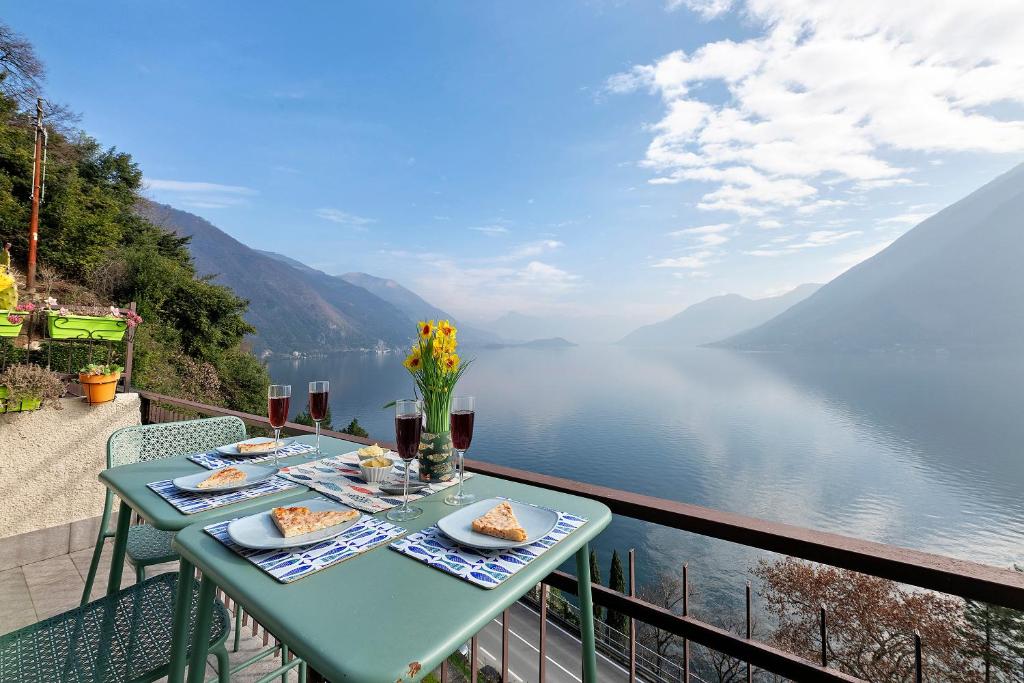 a table with food on a balcony overlooking a lake at La Gabbianella - Lake Como in Argegno