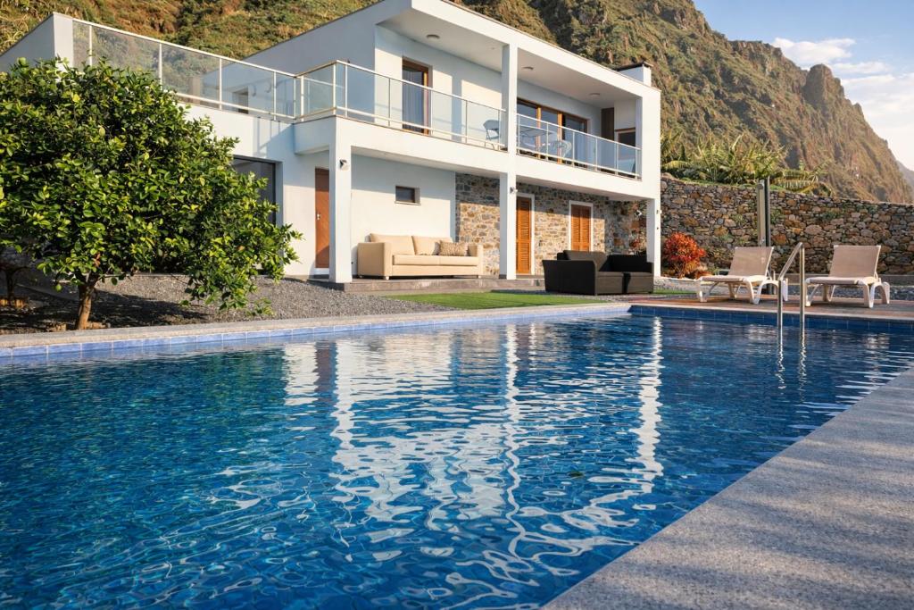 a villa with a swimming pool in front of a house at Villa O Pomar with optional heated pool in Paul do Mar