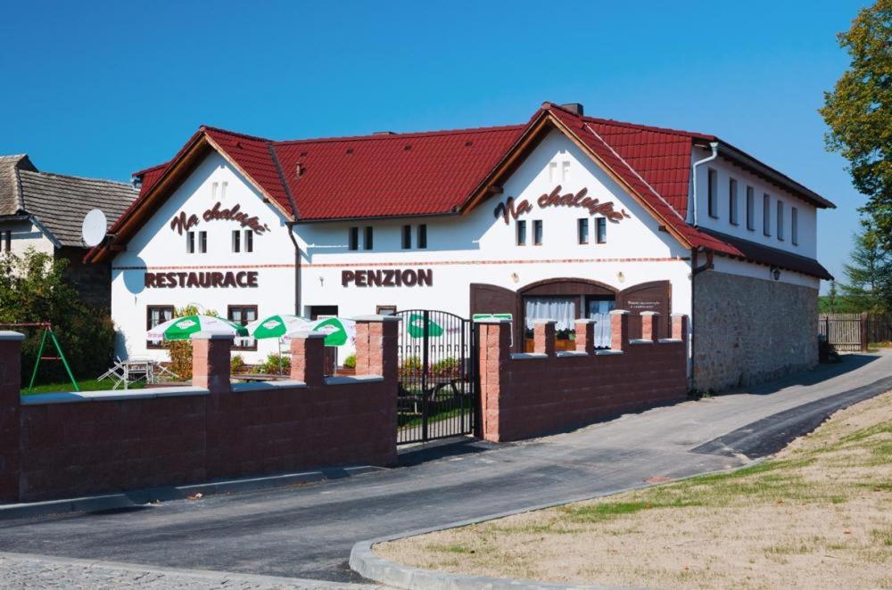 a white building with a red roof and a fence at Penzion Na Chalupě in Polička